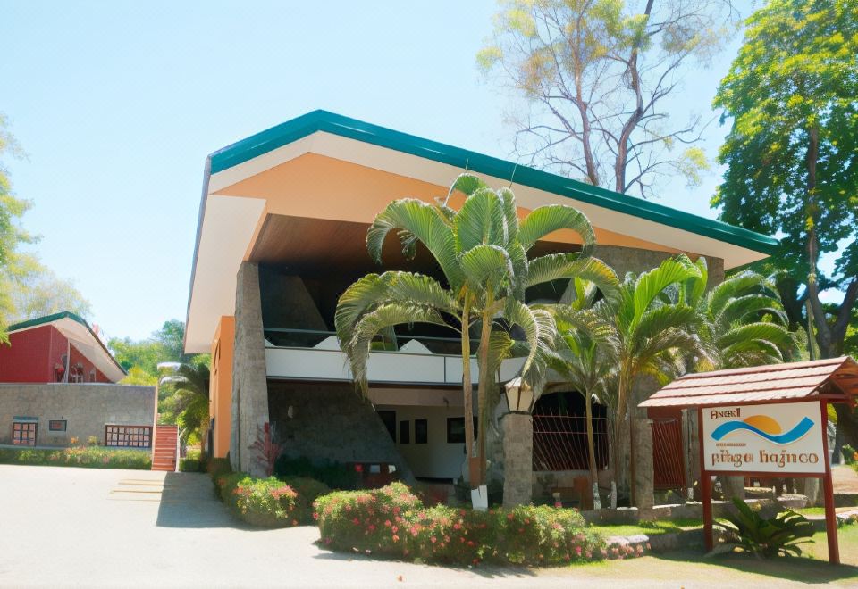 a large building with a green roof and palm trees in front of it , under a clear blue sky at Hotel Playa Bejuco