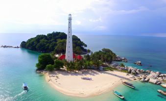 an aerial view of a white lighthouse on an island , surrounded by palm trees and clear blue water at Rock and Wreck Dive Resort