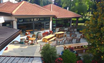 an outdoor seating area with wooden tables and chairs , surrounded by a lush garden and a house at Hotel Panorama