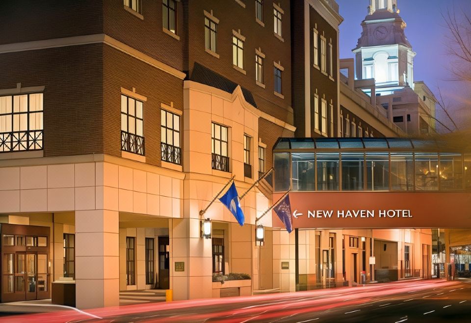 "the exterior of a hotel named "" new haven hotel "" with its red and white facade , lit up at night" at New Haven Hotel