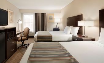 a hotel room with two beds , one on the left and one on the right side of the room at Spring Lake Inn & Suites - Fayetteville