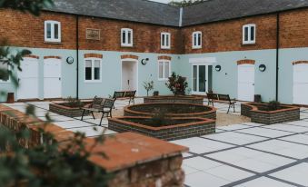 a courtyard with brick walls and brick planters , surrounded by benches and a blue wall at Healing Manor Hotel