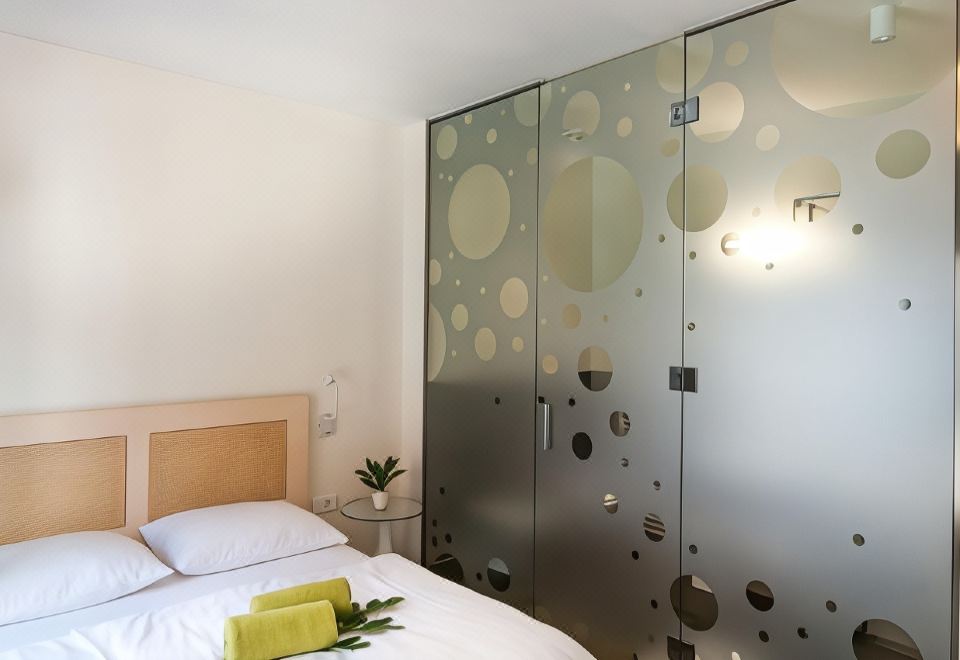 a bedroom with a bed , green plants , and a glass wall with bubbles on it at Art Hotel