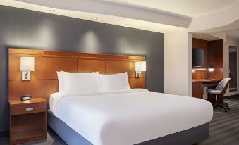 a large , well - made bed with white sheets and a gray headboard is in a hotel room at Courtyard Columbus New Albany