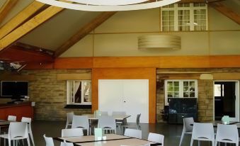 a large room with white tables and chairs , a wooden ceiling , and a television mounted on the wall at Yanchep Inn