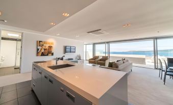 a modern kitchen with white countertops and a large island is shown next to a living area at Sacred Waters Taupo