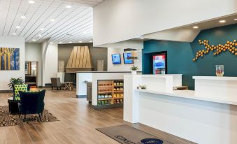 a modern reception area with a desk , wooden flooring , and a blue accent wall , as well as a few tvs and refrigerators at The Kenilworth