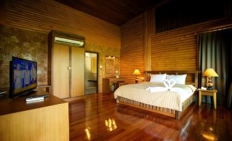 a large bedroom with wooden walls and floors , a bed , dresser , and a lamp on the side at Blues River Resort