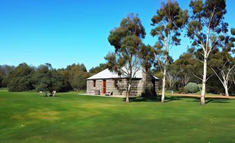 a small wooden house surrounded by green grass and trees , located in a grassy field at Royal Mail Hotel