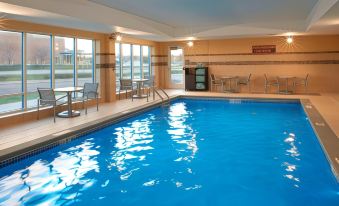 a large indoor swimming pool surrounded by lounge chairs and tables , providing a relaxing atmosphere at TownePlace Suites Grand Rapids Airport