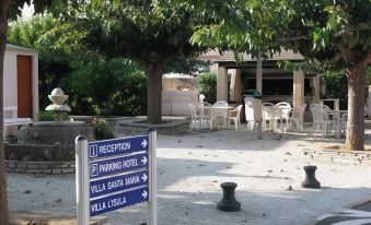 a courtyard with a sign pointing to the entrance of a villa , surrounded by trees and chairs at Stella Marina