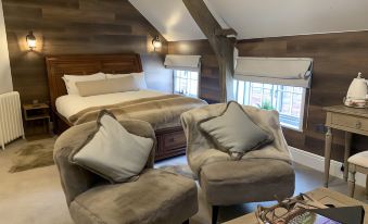 a cozy bedroom with a bed and two chairs , creating a comfortable seating area for relaxation at The Boot Inn