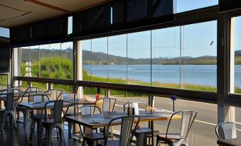a restaurant with a large window overlooking a body of water , providing a scenic view at Rosevears Riverview Hotel