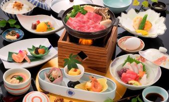 a table is set with various dishes , including sushi and a hot pot filled with raw meat at Hotel Verde