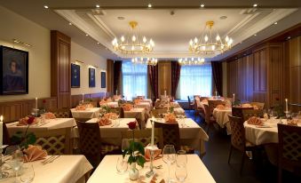 a large dining room with several tables and chairs , all set for a formal dinner at Hotel Post Alpine Cityflair
