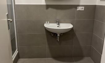 a bathroom with a white sink , gray tiles , and a gray carpet with a marble border at Hotel Zur Post Limburg Bad Camberg