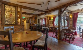 a dining room with a wooden table , chairs , and a bar area in the background at The Barford Inn