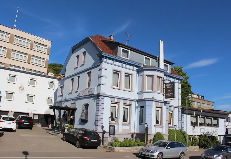 a blue building with a red roof is situated on a street corner , surrounded by cars and trees at Hotel Restaurant Post Italia