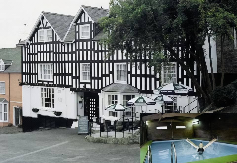 a large black and white building with a pool in front of it , surrounded by trees at The Dragon Hotel