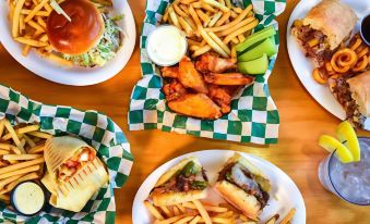 a table is filled with various plates of food , including burgers , fries , and chicken nuggets at Best Western Space Shuttle Inn