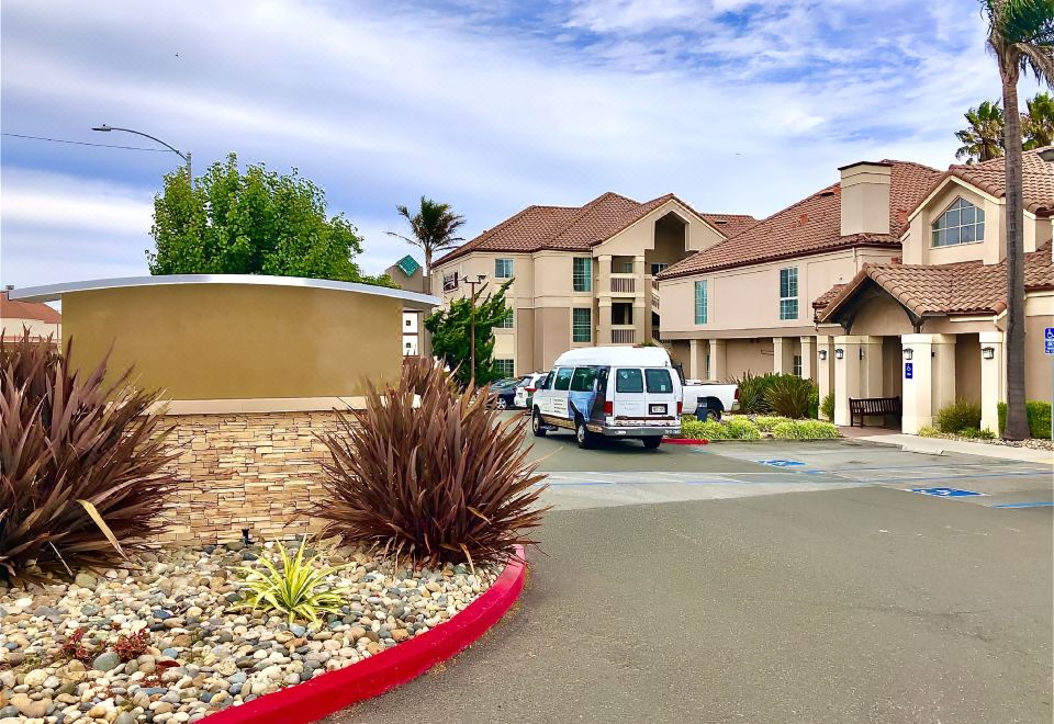 a van is parked in front of a building with a large stone wall and red curb at Sonesta ES Suites San Francisco Airport San Bruno