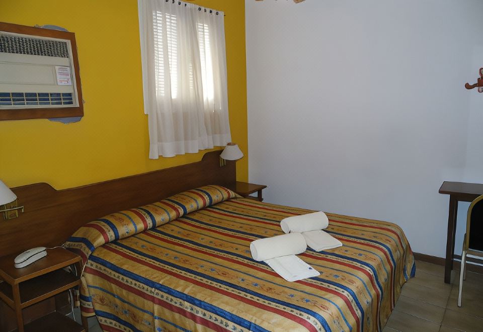 a bed with a striped blanket and two white towels on it is in a room with yellow walls at Hotel San Francisco
