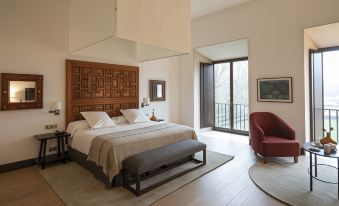 a spacious bedroom with hardwood floors , a large bed , and a sliding glass door leading to a balcony at Parador de Leon - San Marcos