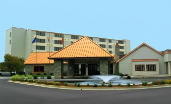 a large hotel with an orange roof and fountain in front of it , under a clear blue sky at Four Points by Sheraton Saginaw