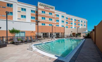 a large swimming pool is located in front of a hotel , with several lounge chairs and umbrellas around it at Courtyard LaGrange