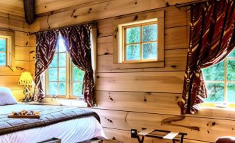 a bedroom with wooden walls and a bed , next to a window with brown curtains at Lake Rabun Hotel