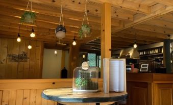 a wooden bar with a round table in the center , surrounded by chairs and stools at Logis le Chalet