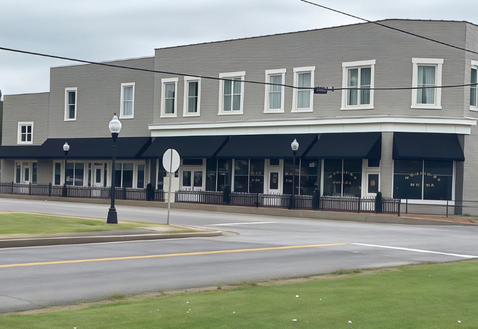 a building with a gray facade and black awnings is located on a street corner at Meadows Hotel