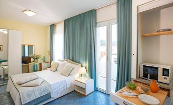 a well - lit bedroom with blue curtains , white beddings , and a bed , along with other furniture including a tv , coffee table , at Hotel L'Approdo