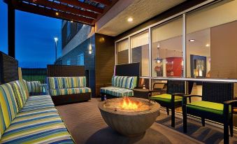 an outdoor patio with a fire pit surrounded by couches and chairs , creating a cozy atmosphere at Home2 Suites by Hilton Baton Rouge