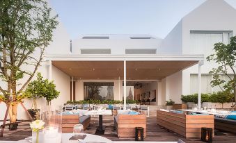 a modern , white - washed building with large windows and outdoor dining areas under a wooden canopy , set against a clear blue sky at Sala Ayutthaya