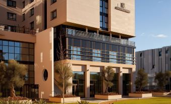 a modern hotel building with multiple floors , surrounded by greenery and set against a clear blue sky at Renaissance Aix-en-Provence Hotel