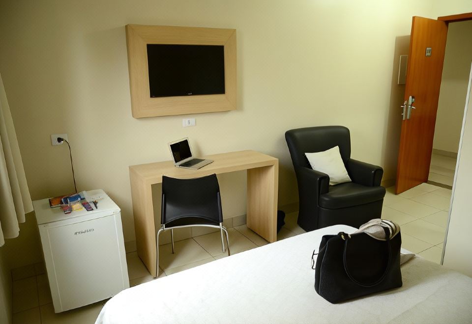 a hotel room with a bed , desk , chair , and a tv mounted on the wall at Hotel Capital