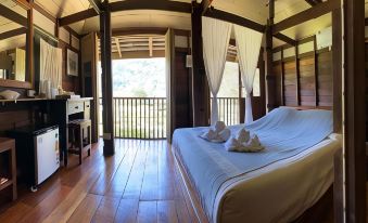 a spacious bedroom with a large bed , hardwood floors , and a balcony overlooking a mountainous landscape at Lhongkhao Samoeng by Chi Villa