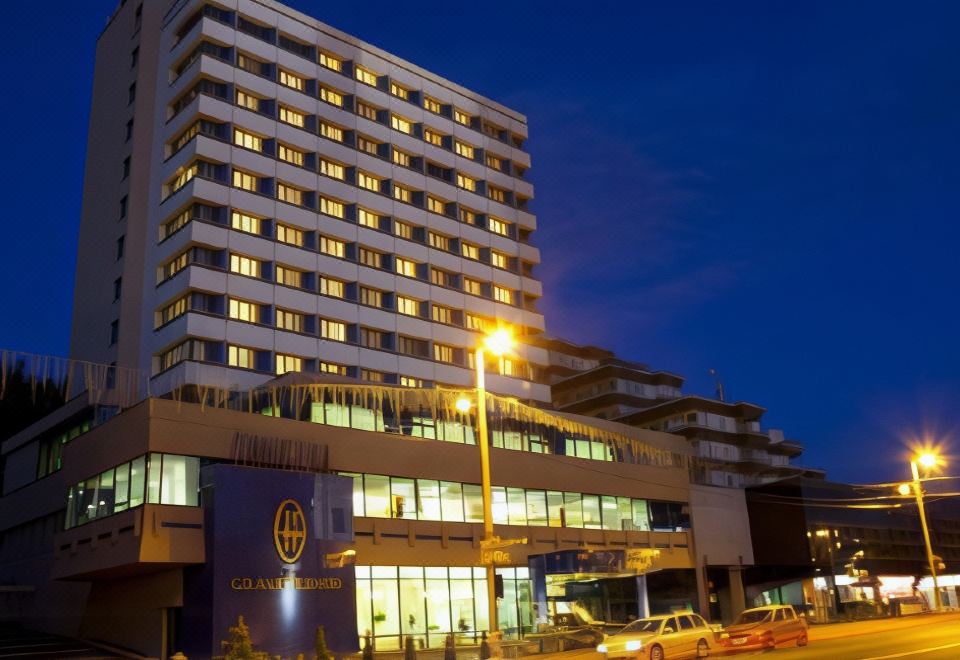 a large , modern hotel building with multiple floors and a yellow light on the side at Grand Hotel