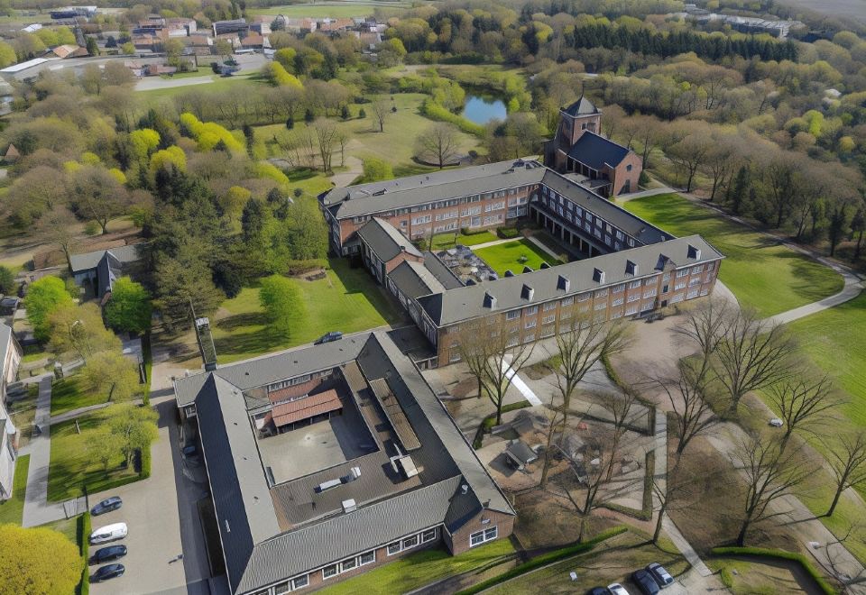 aerial view of a large building surrounded by trees and grass , located in a rural area at Fletcher Kloosterhotel Willibrordhaeghe