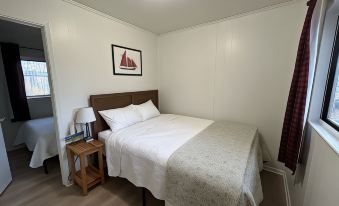 a cozy bedroom with a white bed , wooden floor , and a red framed picture on the wall at Hidden Haven Cottages