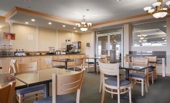 a dining area with multiple tables and chairs , as well as a kitchen area with appliances at Lighthouse Suites Inn