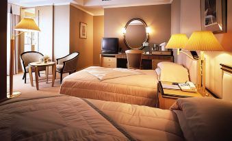a hotel room with two beds , a desk , chairs , and a television , all decorated in warm colors at Imabari Kokusai Hotel