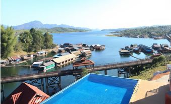 a blue swimming pool is situated on a deck overlooking a body of water with boats and mountains in the background at Samprasob Resort