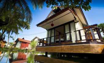 a wooden house with a balcony overlooks a flooded area surrounded by trees and water at Lampam Resort