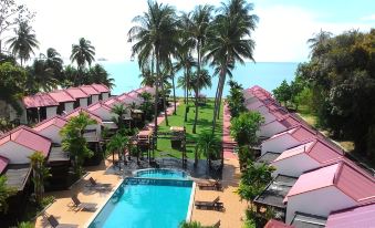 a resort with a pool surrounded by palm trees and a view of the ocean at Shah's Beach Resort Malacca