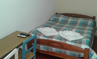 a bed with a blue and white checkered blanket is next to a small desk at Alquimia