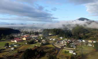 an aerial view of a small town surrounded by mountains , with a body of water in the foreground at Zeehan Bush Camp