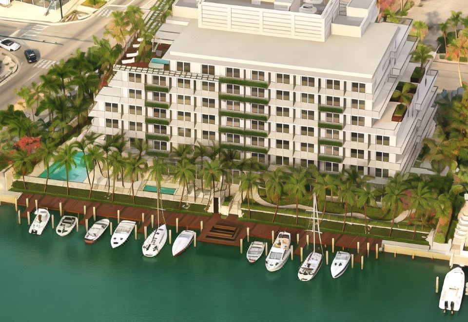 a bird 's eye view of a modern building with boats docked in front and palm trees lining the shore at Grand Beach Hotel Bay Harbor