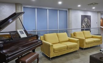 a modern living room with yellow sofas and a piano , creating a warm and inviting atmosphere at Hotel Concorde